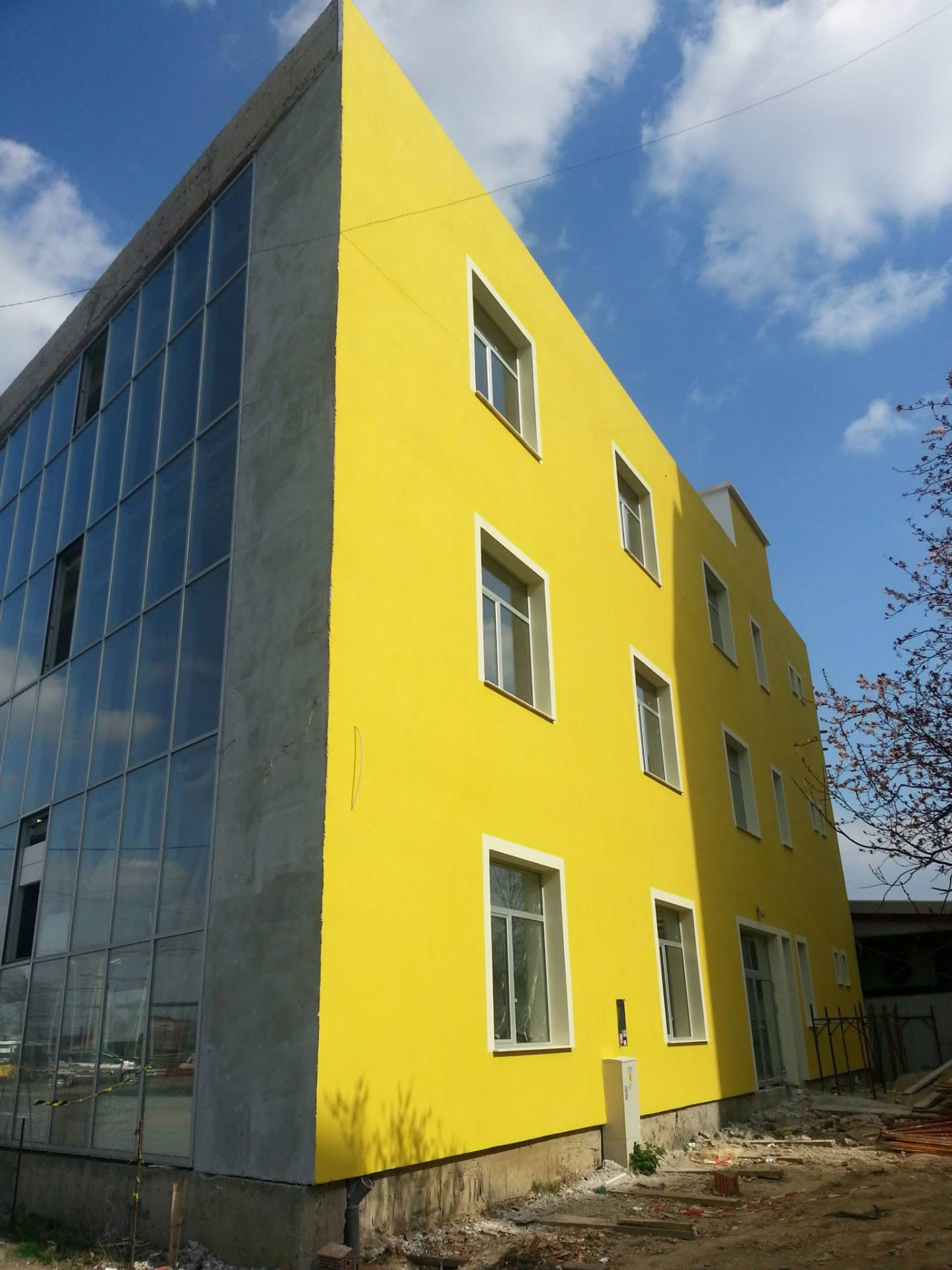 Clădire de birouri finalizată, fațadă galbenă termoizolată și perete cortină